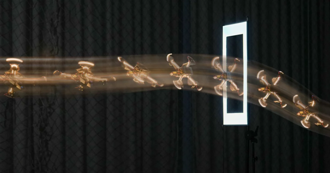 A quadrotor tilting to fly through a narrow illuminated opening
